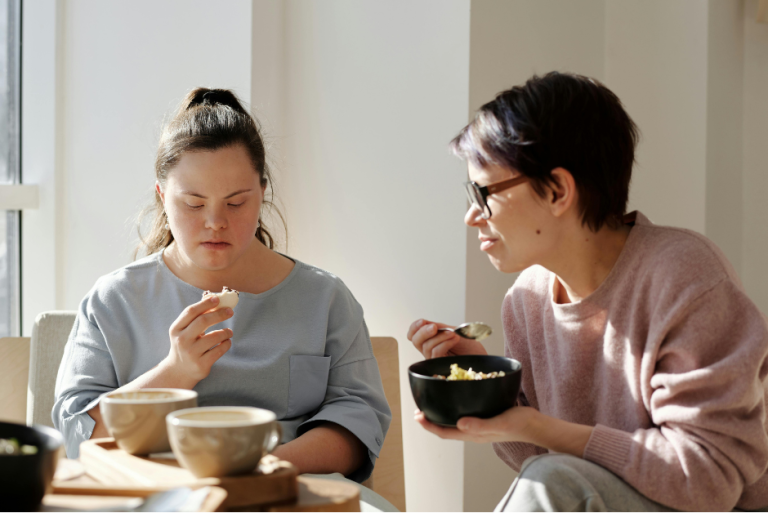 Participant examines her food while her support worker looks on Assist Daily Activities MasRic Health Registered NDIS Service Provider in Geelong and Surf Coast