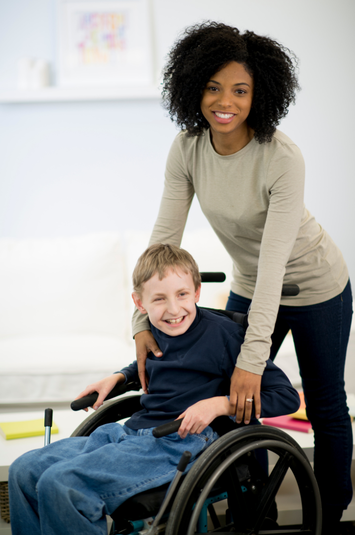 Support worker standing up with a disabled child on a wheelchair MasRic Health Registered NDIS Service Provider in Geelong and Surf Coast